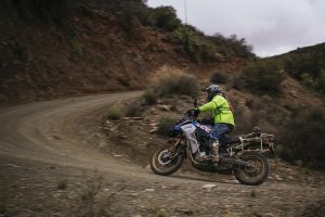 A man in a high-vis rain jacket rounding a corner on his BMW F850GS Adventure